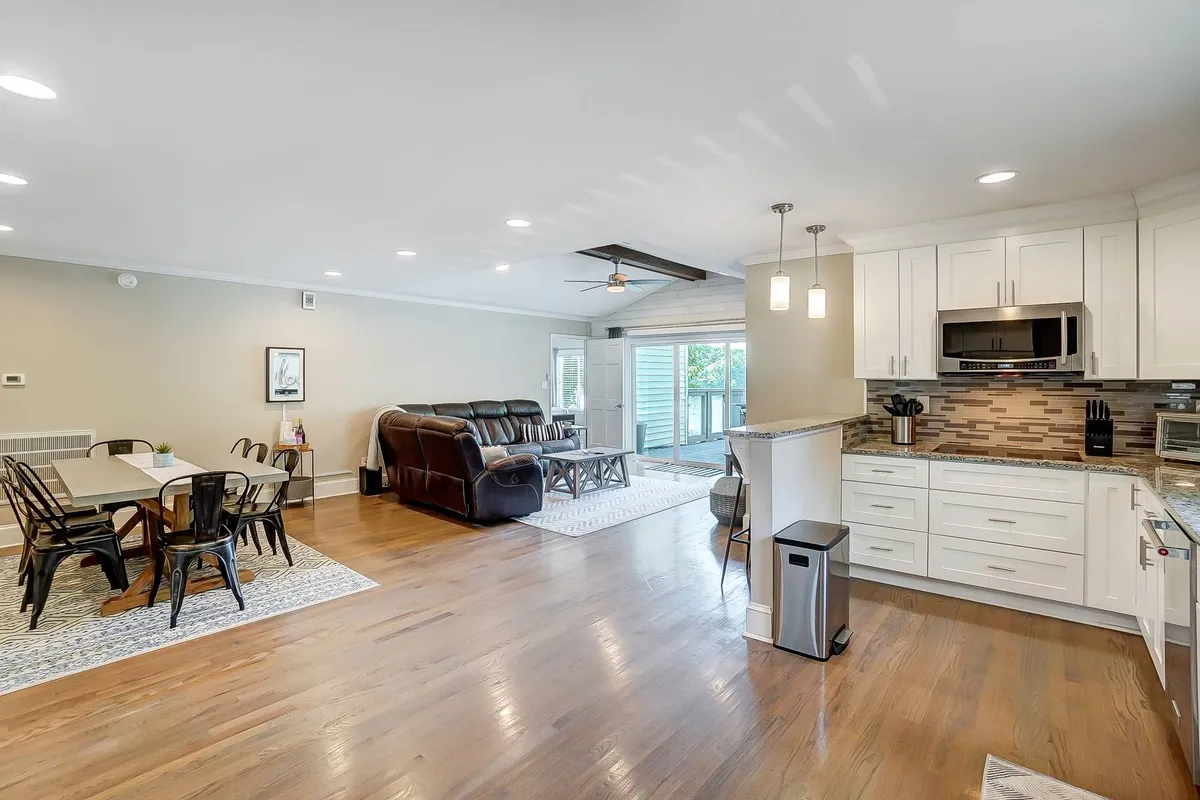 An open-plan space with a dining table, reclining sofa, and a kitchen island, designed for gatherings, meals, and entertainment. The layout encourages productivity and socialization, suitable for both business retreats and extended family stays.