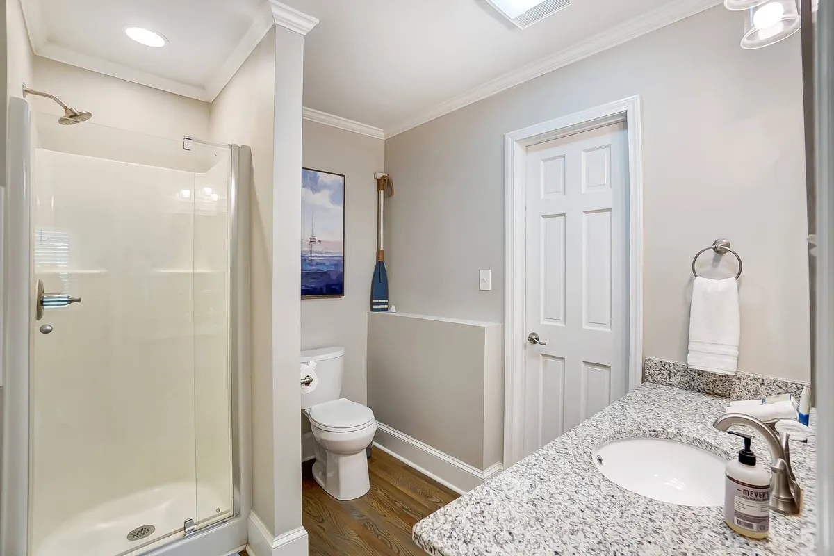 A modern bathroom boasting a glass shower, granite countertop, and framed artwork. The clean lines and stylish fixtures create a spa-like environment, perfect for unwinding after a day of riverfront adventures.