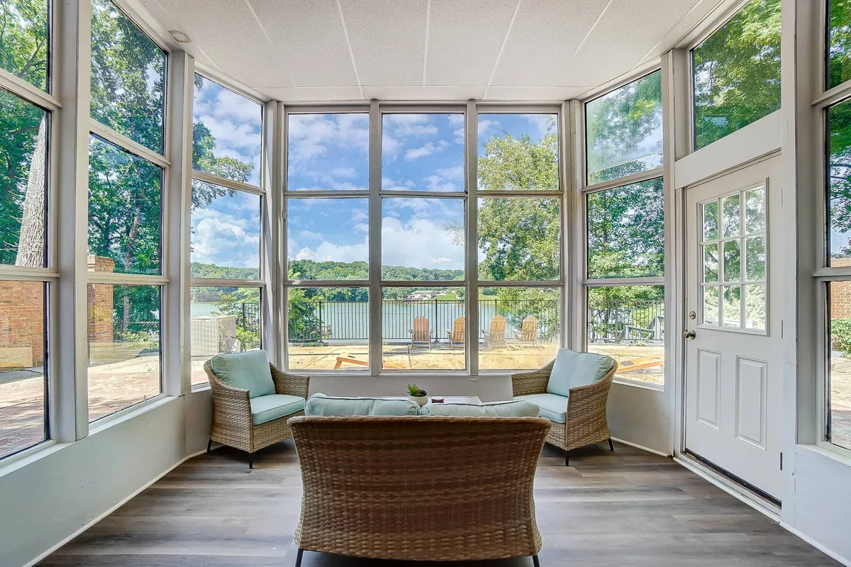 A comfortable seating area is positioned beside large windows showcasing a scenic view of the lake or riverfront. The room invites guests to unwind while soaking in natural views, suggesting both relaxation and the enjoyment of panoramic water vistas even from inside.