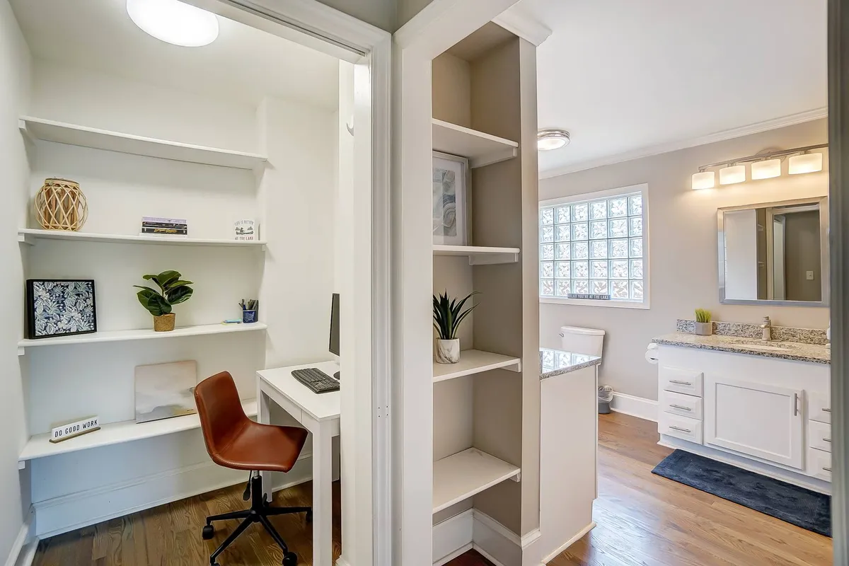 A dedicated workspace within the bedroom, featuring a desk with a computer, open shelves for organization, and a vanity area. The setup is practical yet inviting, perfect for business travelers or guests needing a quiet spot to work or study.