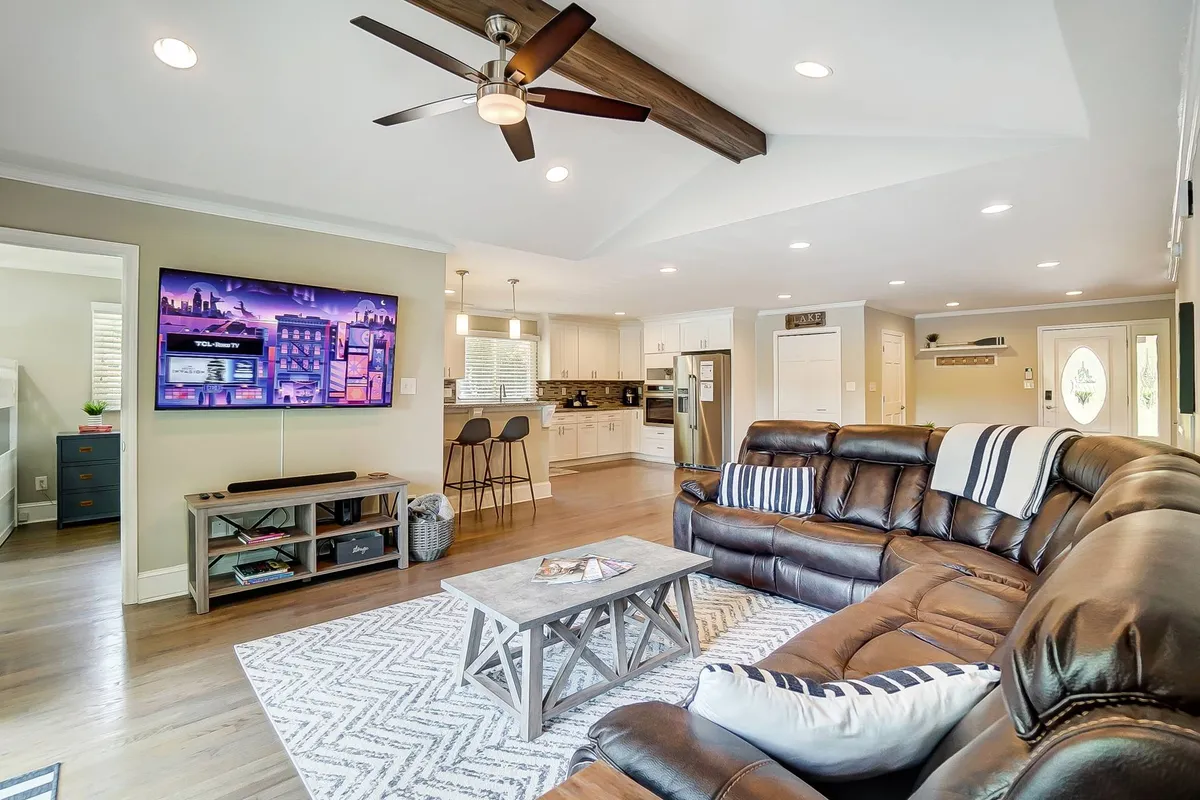 A cozy living area featuring a sofa, coffee table, and TV, with the kitchen visible in the background. The setup encourages movie nights, casual dining, and relaxed family time within an open-plan environment.